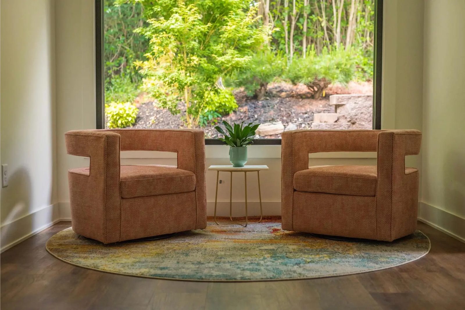 Two terracotta armchairs beside a garden window in the Greenville office
